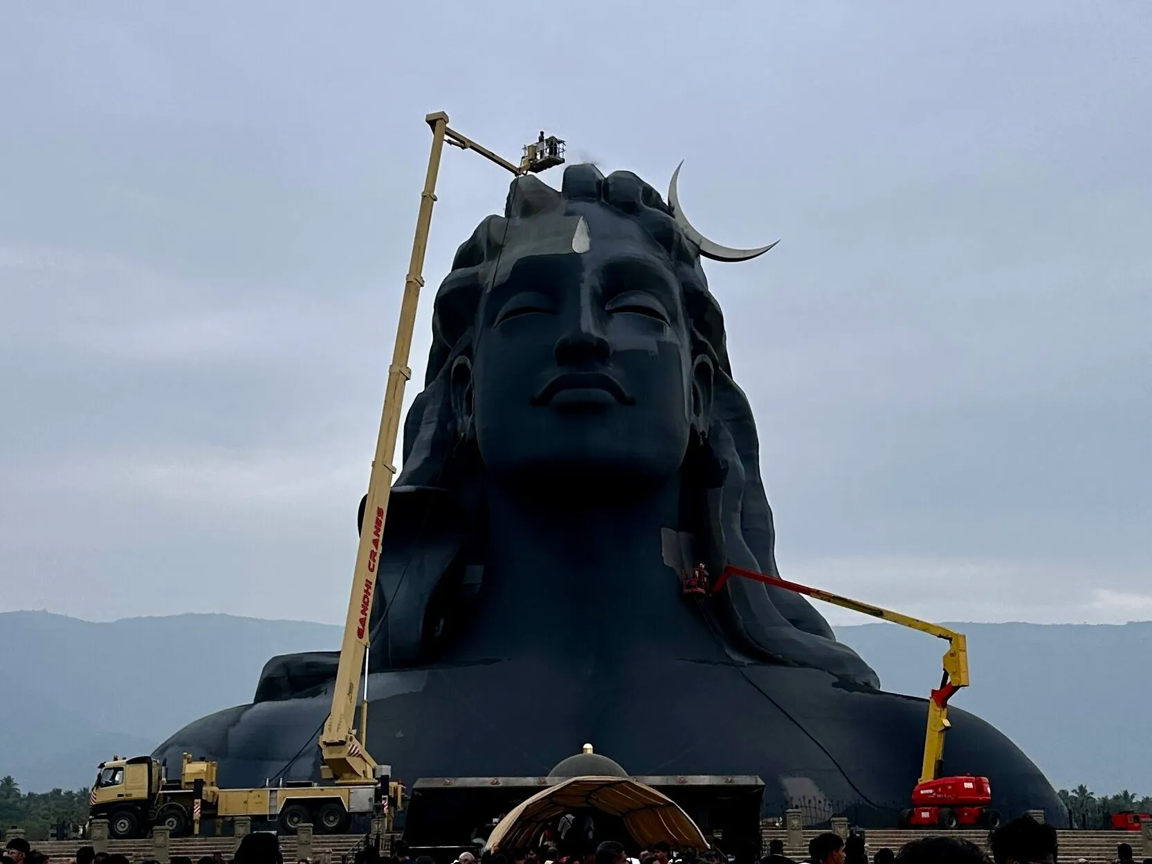 The massive 34-meter Adiyogi statue during daytime with cranes for maintenance