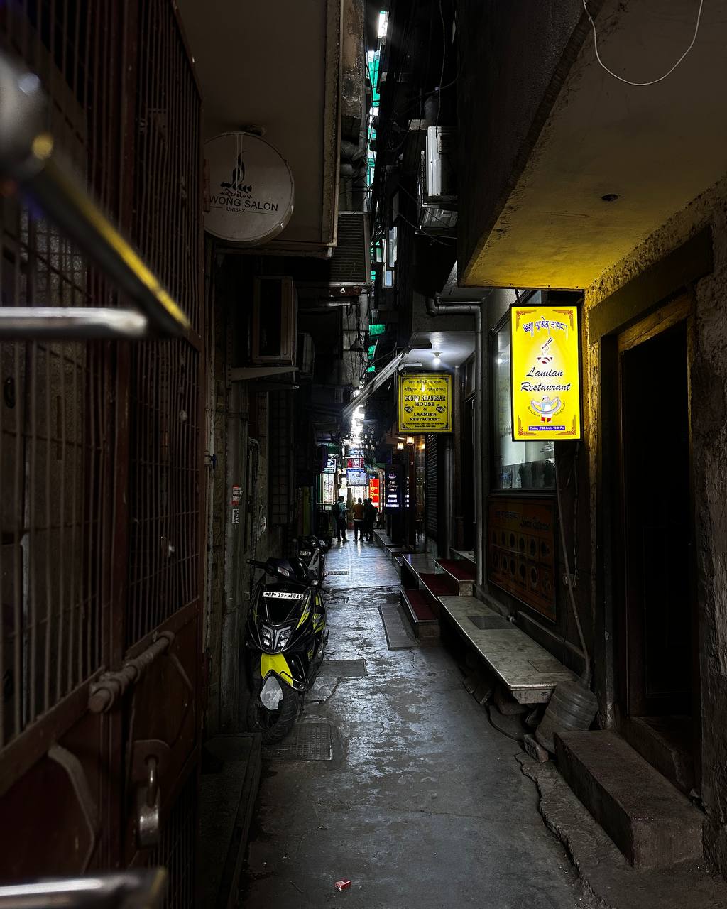 Narrow alley at night with restaurant signs glowing